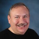 A portrait of Dr. David Wolff smiling while wearing a dark top.
