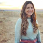 Melina Alden, licensed marriage and family therapist at Melina Alden, LMFT standing among a desert and smiling with long dark hair while wearing a light blue top and pink waistband.