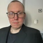 Rickard Osterholm wearing glasses and a black blazer over a black shirt.